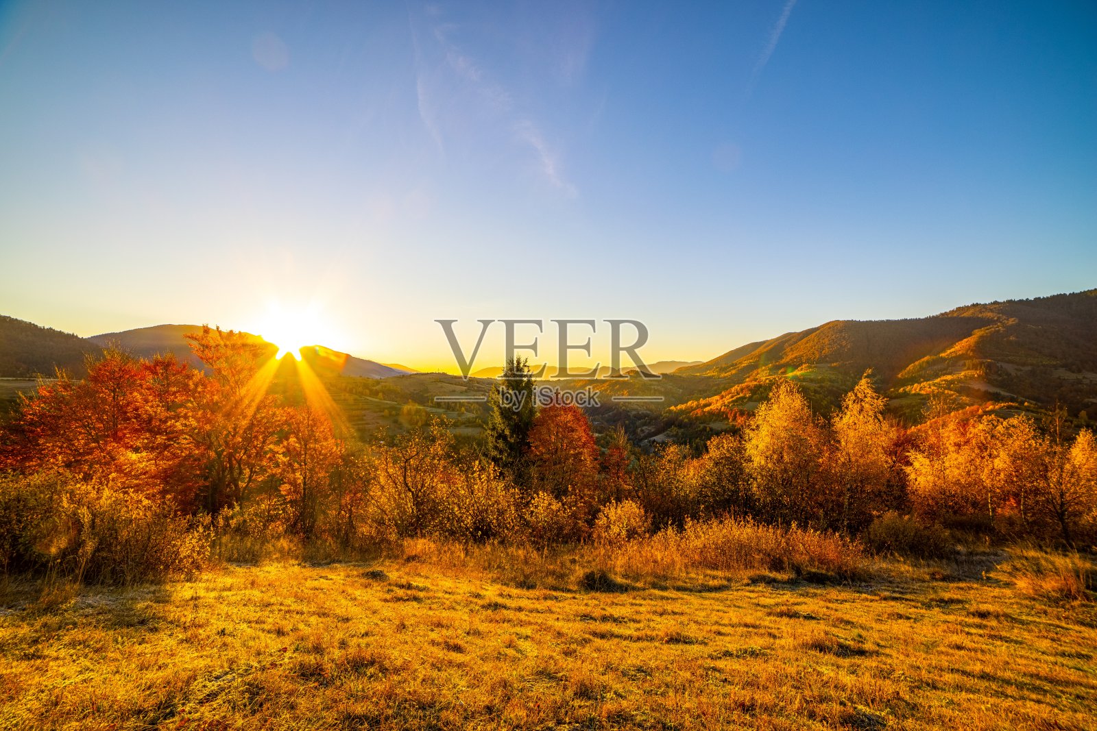 秋天，太阳落在森林山的背后照片摄影图片