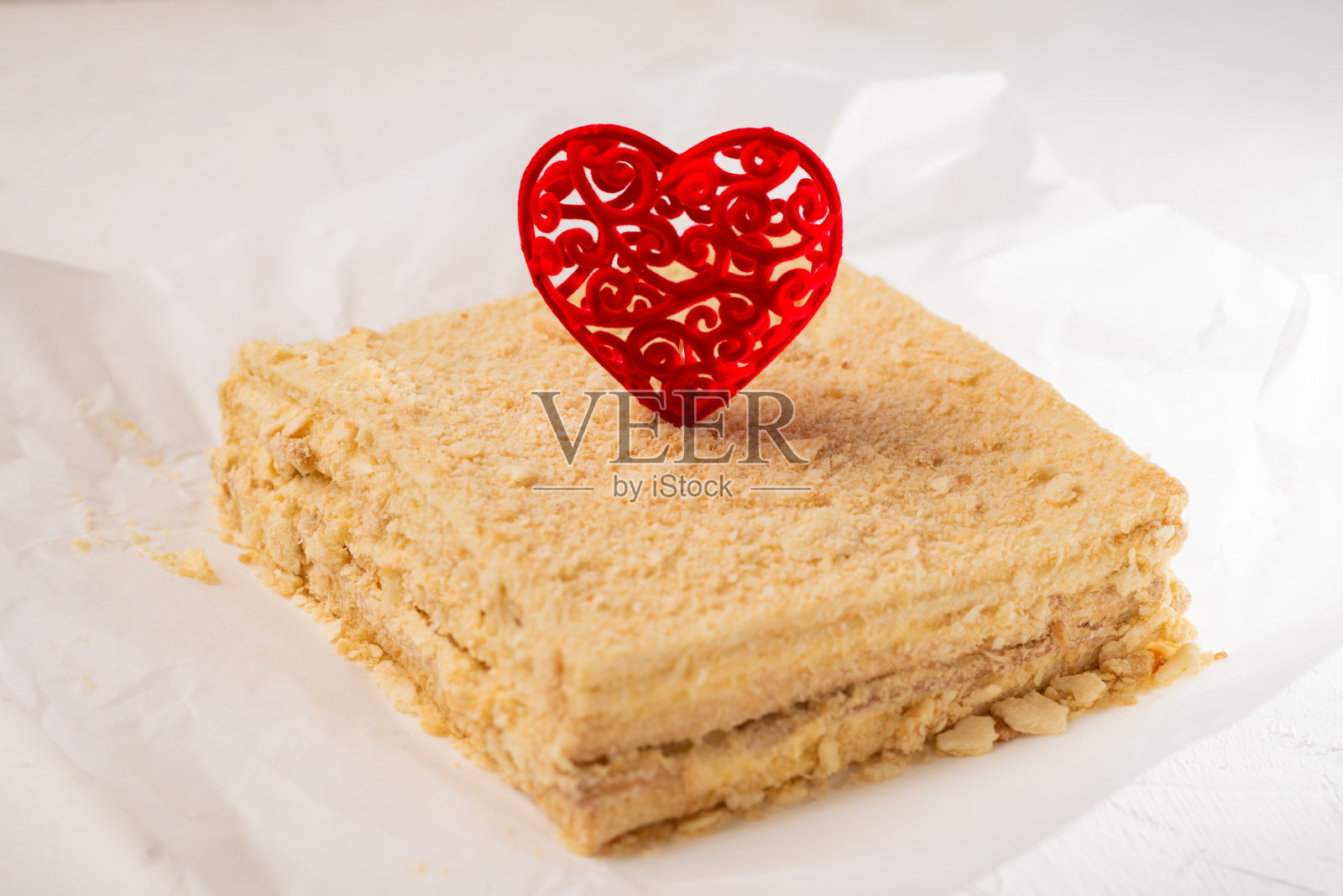 红心蛋糕。素食拿破仑蛋糕配上情人节的装饰。简约的设计。白色背景。照片摄影图片