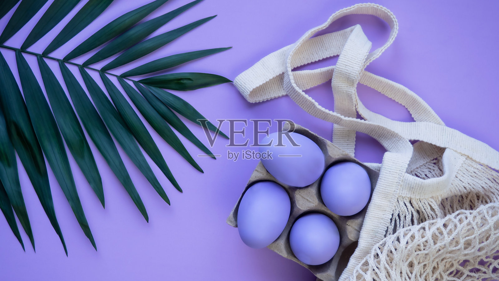 丁香色背景的复活节彩蛋。复活节。环保网状购物袋。照片摄影图片