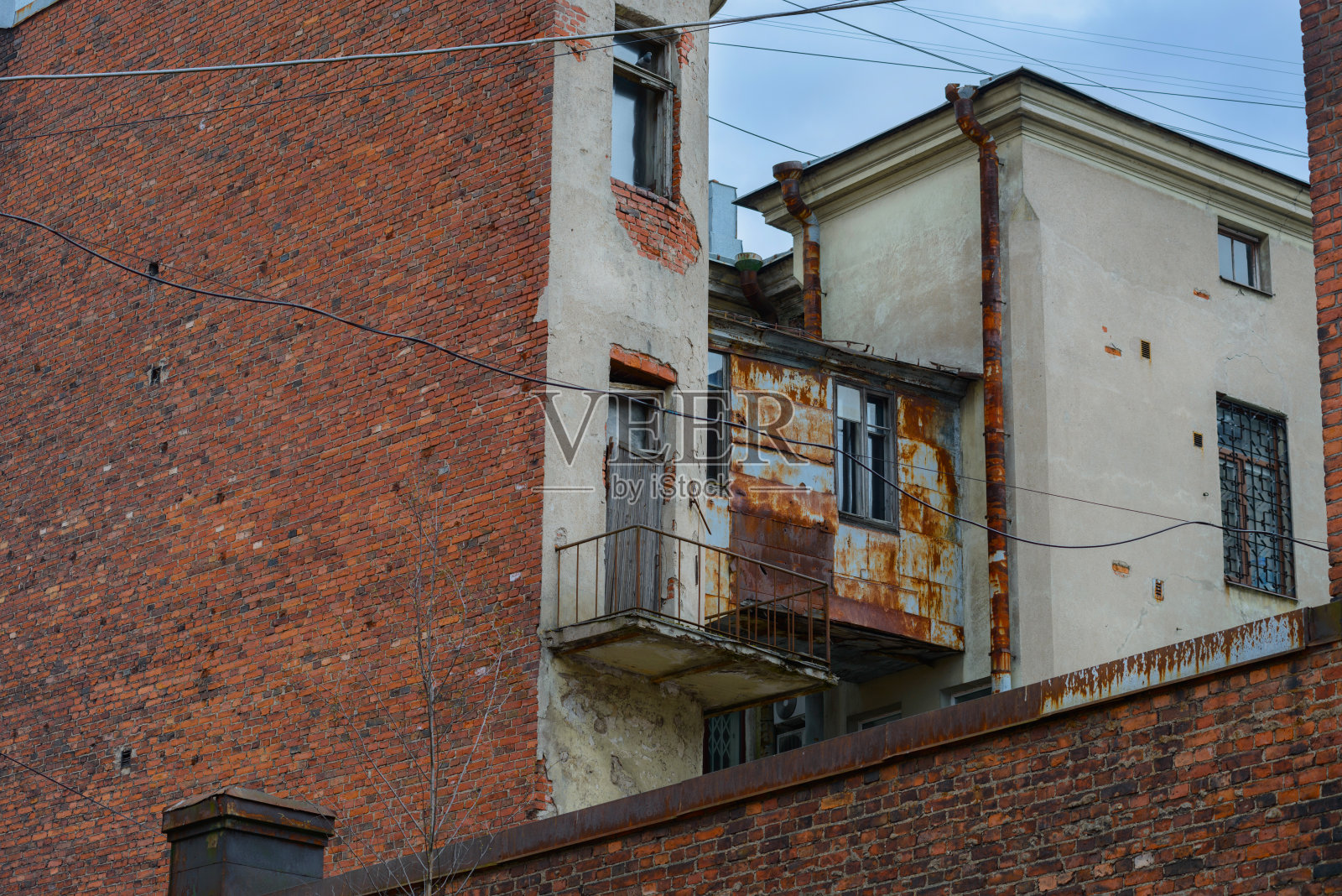 维堡建筑里阴暗的庭院。生锈的排水管、旧砖、有铁条的窗户和被生锈的锡堵塞的人行道。照片摄影图片