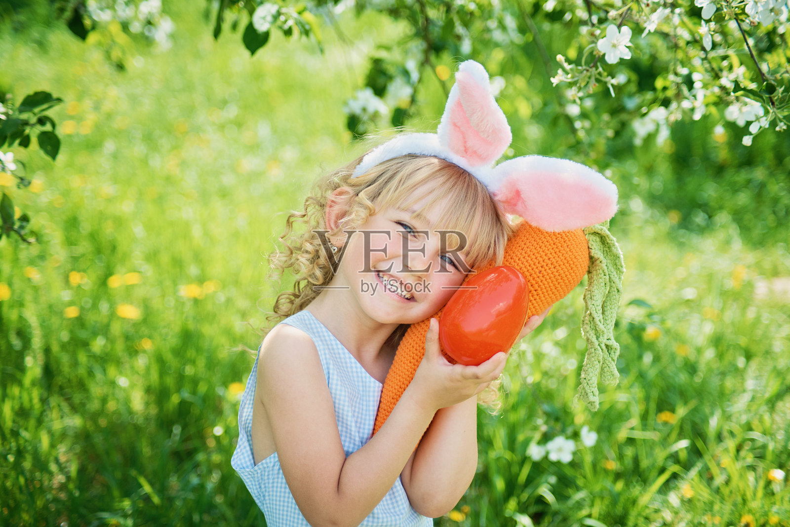 可爱有趣的女孩，带着复活节彩蛋和兔子耳朵在花园里。复活节的概念。在复活节找彩蛋时大笑的孩子照片摄影图片