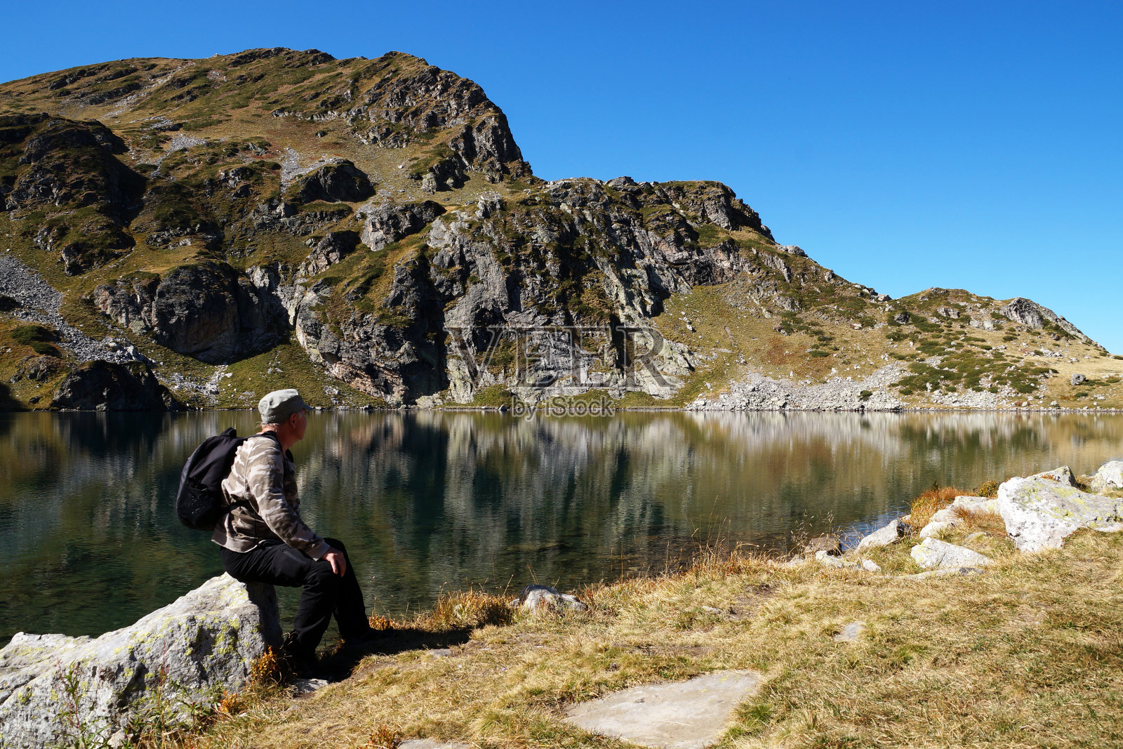 一个人坐在一块石头上欣赏山上的湖照片摄影图片