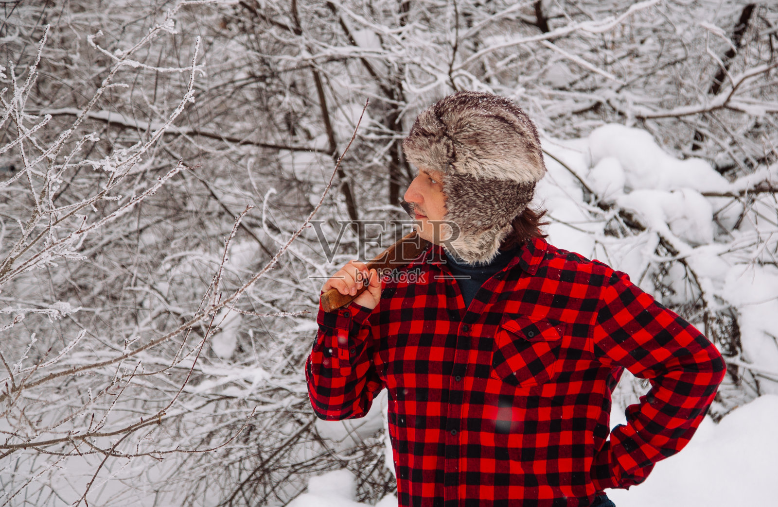 冬天雪林里的伐木工人。潮人用斧头。伐木工人的生活方式。在森林里工作的帅哥。照片摄影图片