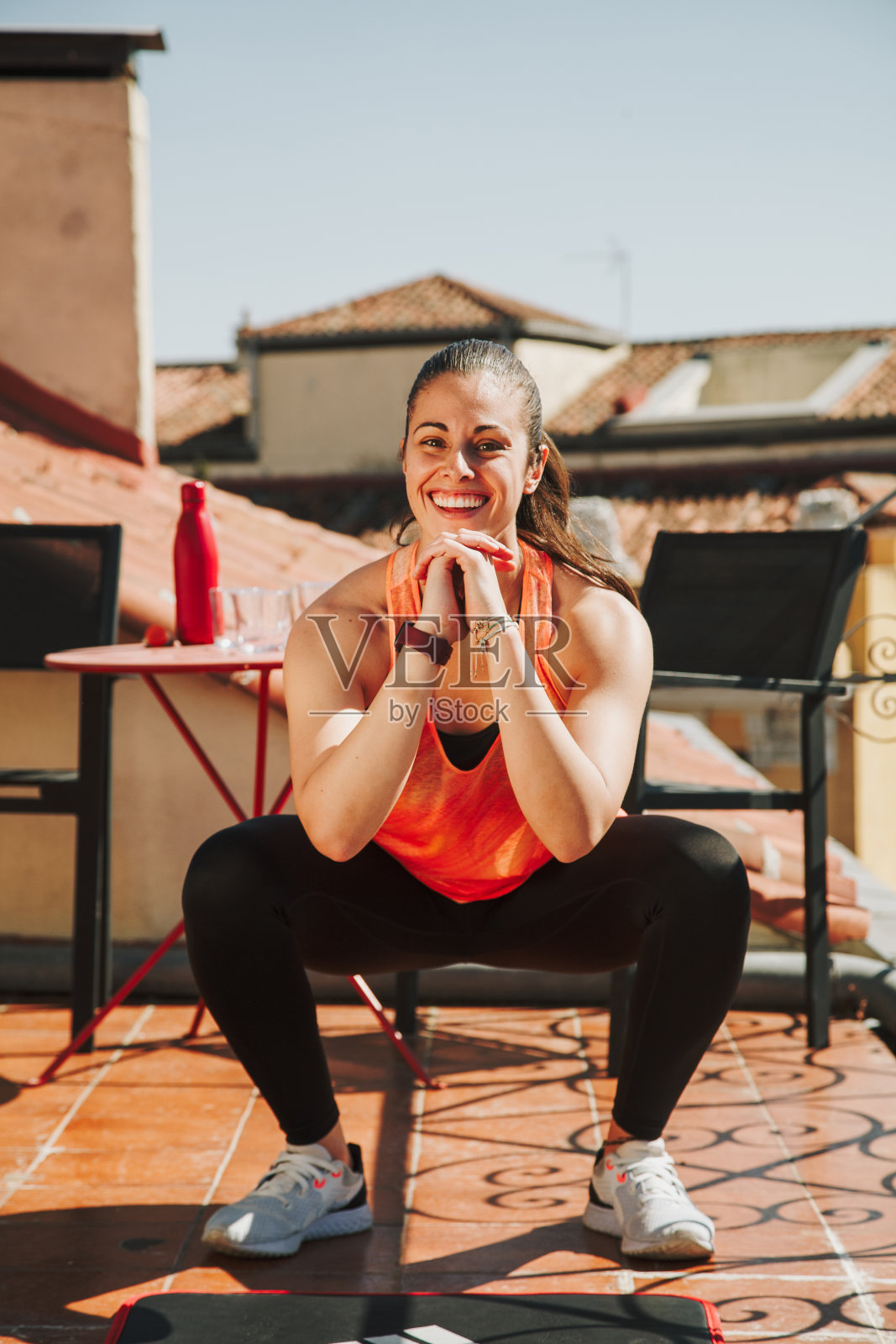 一个女人在楼顶露台上做深蹲运动照片摄影图片