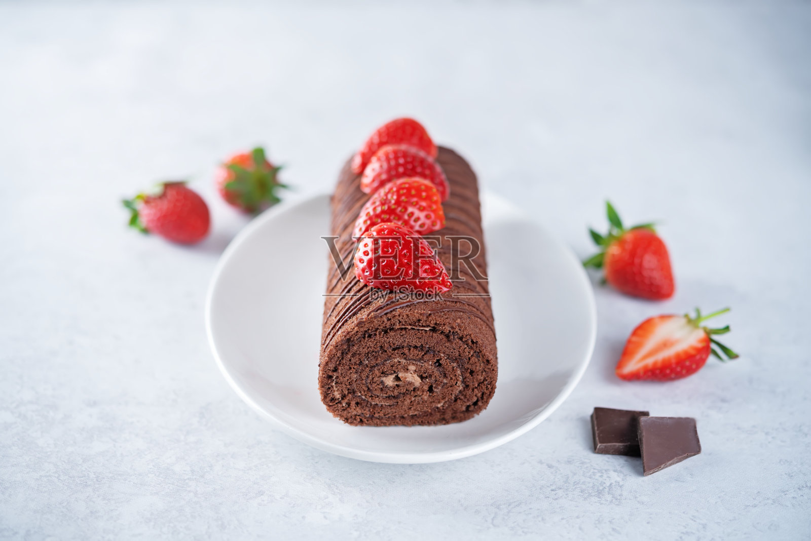 巧克力蛋糕卷和新鲜草莓放在盘子里照片摄影图片