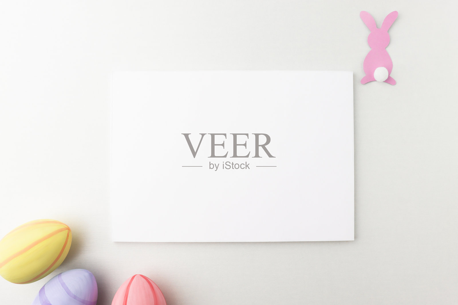 模拟复活节节日的问候与纸兔子和彩色鸡蛋在一个木制的桌子上，俯视图。空白模板与复制空间在最小的风格，平lay。照片摄影图片