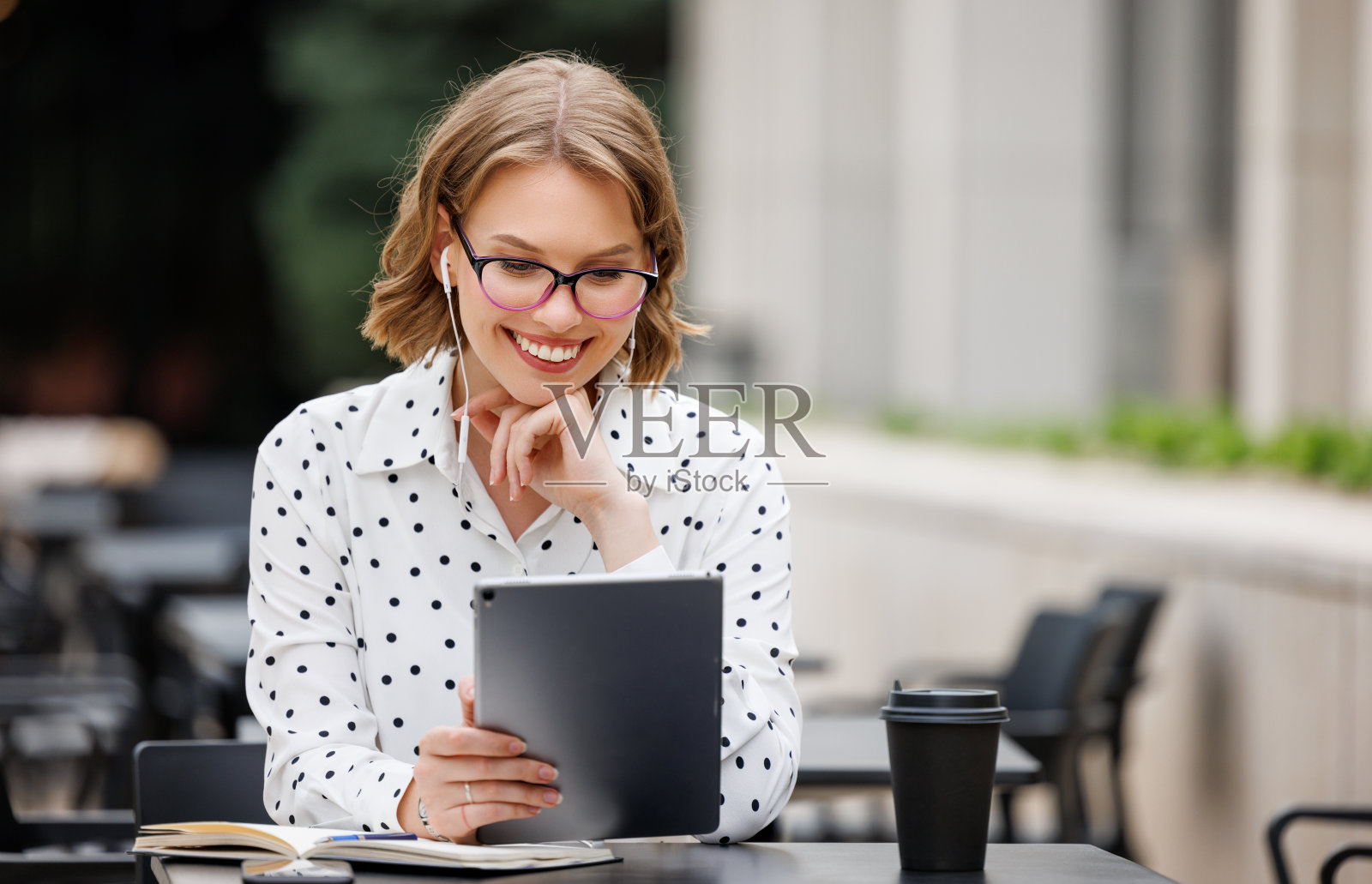 快乐的年轻女教师戴着耳机坐在平板电脑前上网上课照片摄影图片