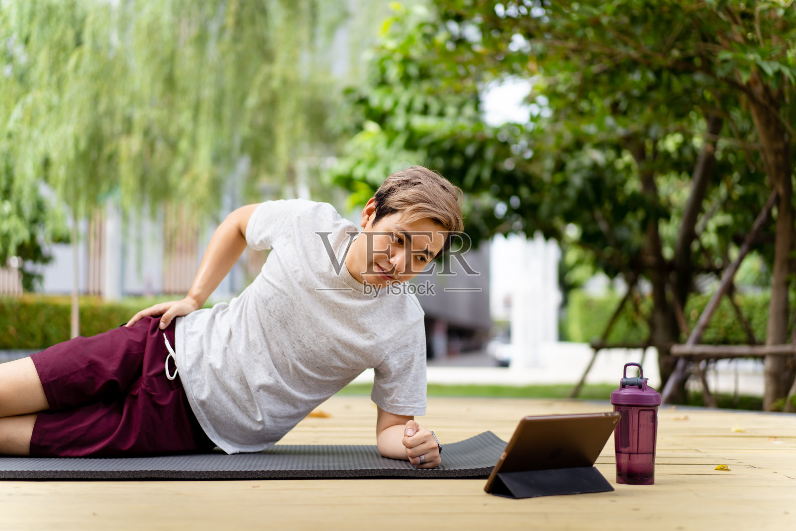 亚洲男子使用平板电脑进行体重锻炼。照片摄影图片