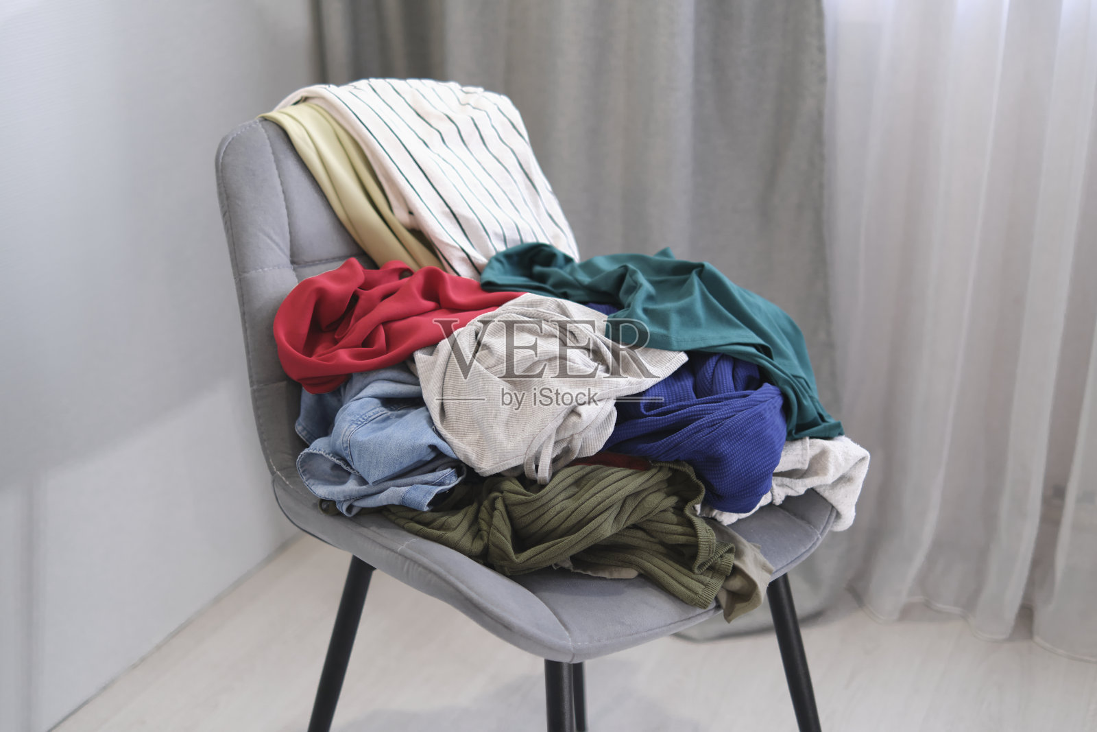 人把用过的衣服扔在椅子上。把衣服堆在椅子上。一堆用于捐赠和回收的旧衣服。极简主义的概念，混乱和衣柜清洁照片摄影图片