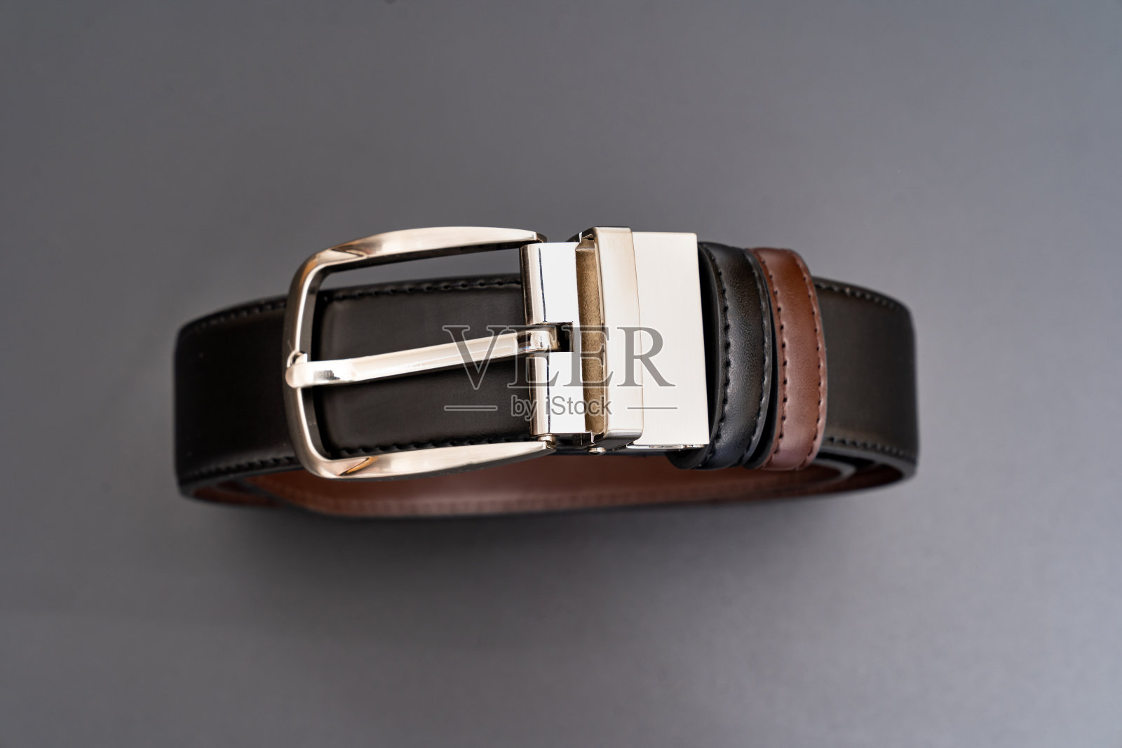 双面黑色和棕色皮革带与一个钮扣黑色扣。照片摄影图片