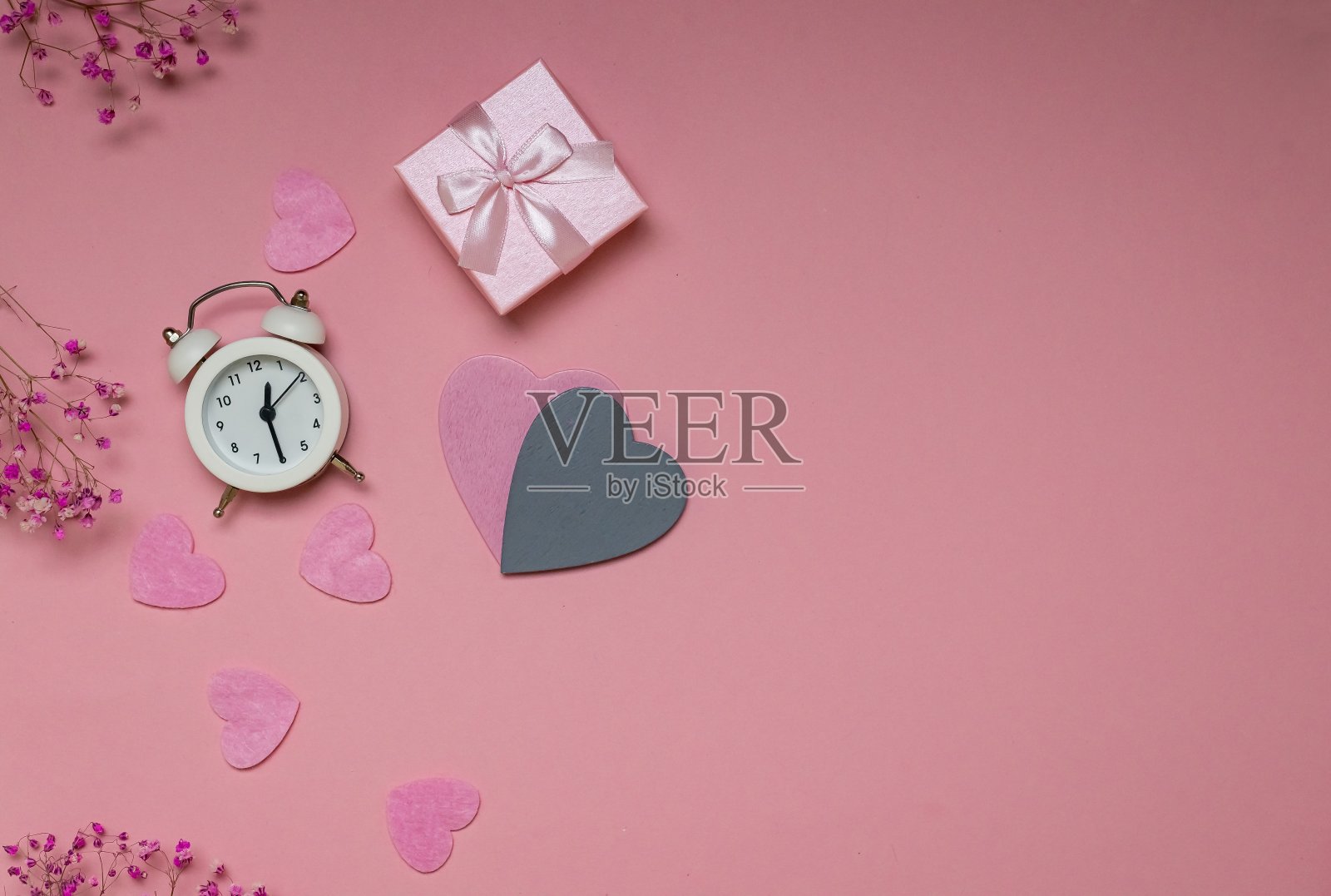 情人节作文:一份礼物，一个闹钟，粉色背景上的心形。从上面的观点照片摄影图片