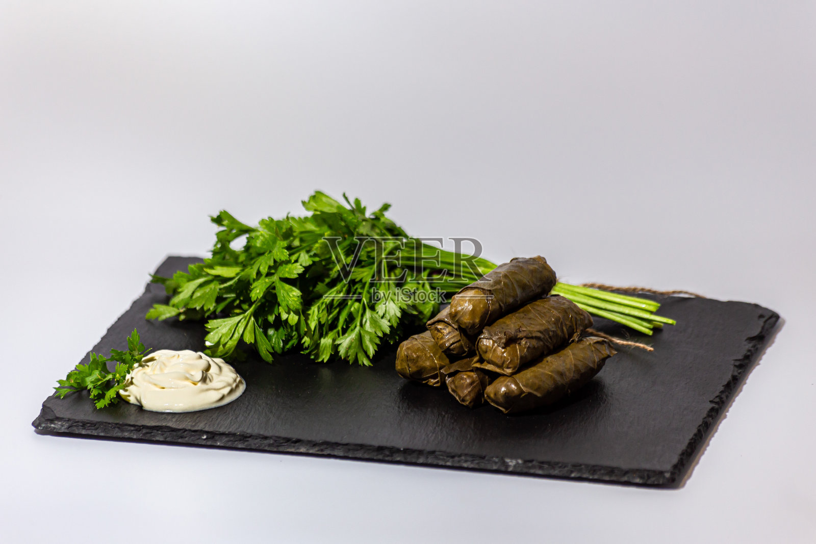 传统的格鲁吉亚朵玛，黑色石板上放着酸奶油和香草，香菜和香菜照片摄影图片