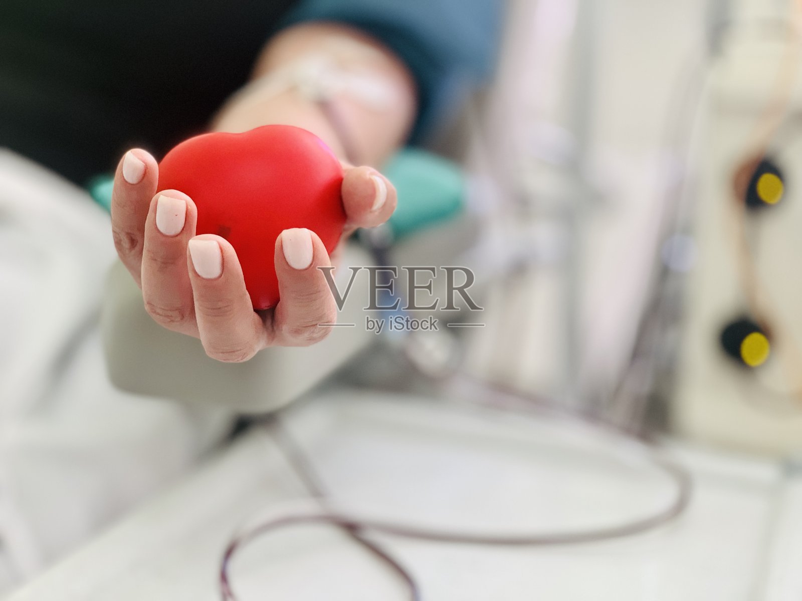 一个献血者把一颗红心捏在手里的特写镜头。世界献血者日。拯救生命。照片摄影图片