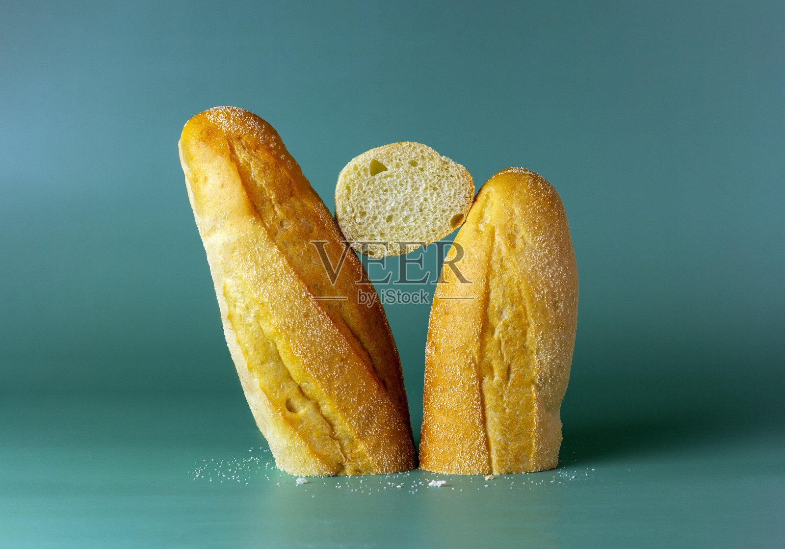 新鲜出炉的美味法棍面包在绿色的背景上。照片摄影图片