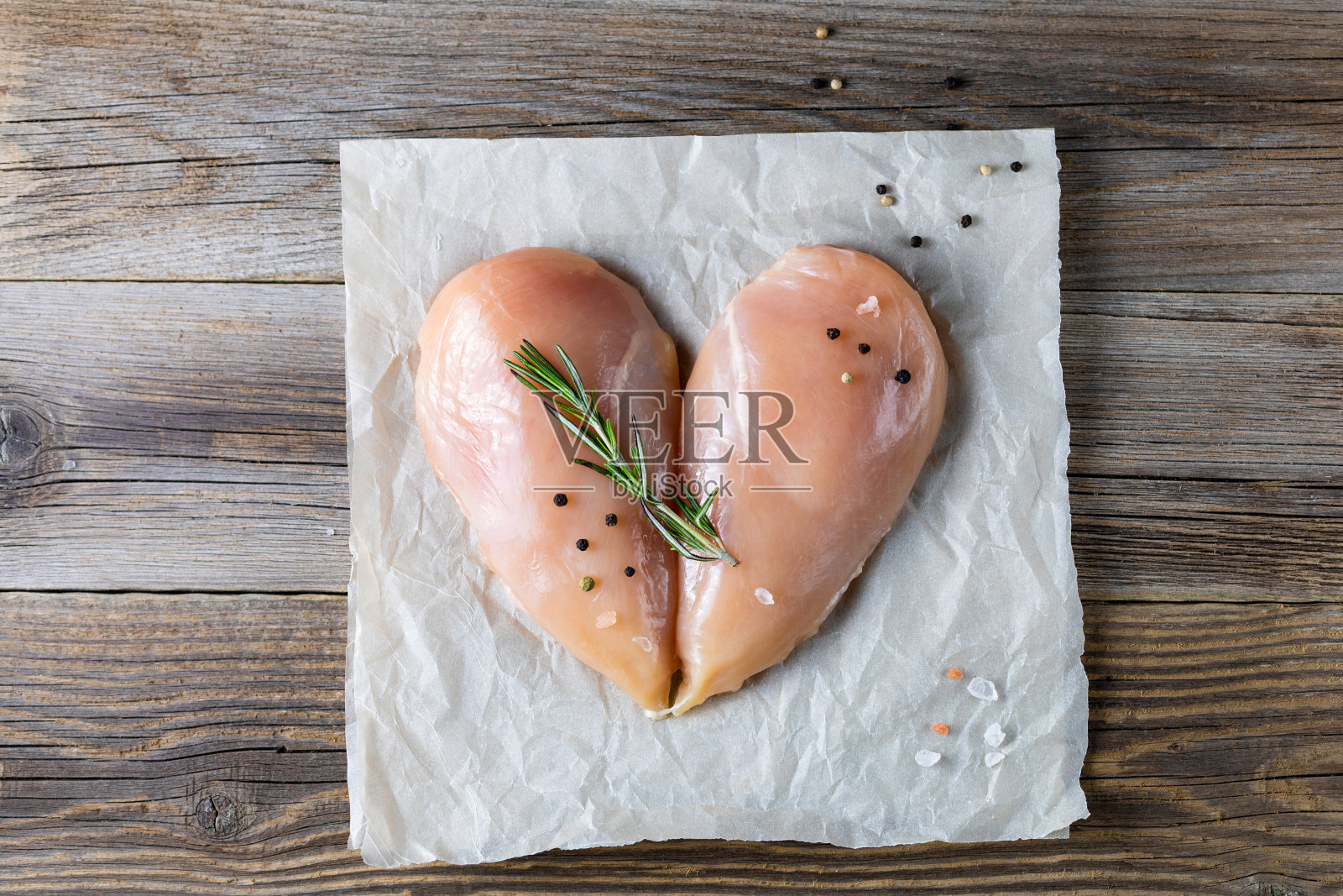生鸡柳在一个心形与迷迭香和香料的自然木制背景。照片摄影图片