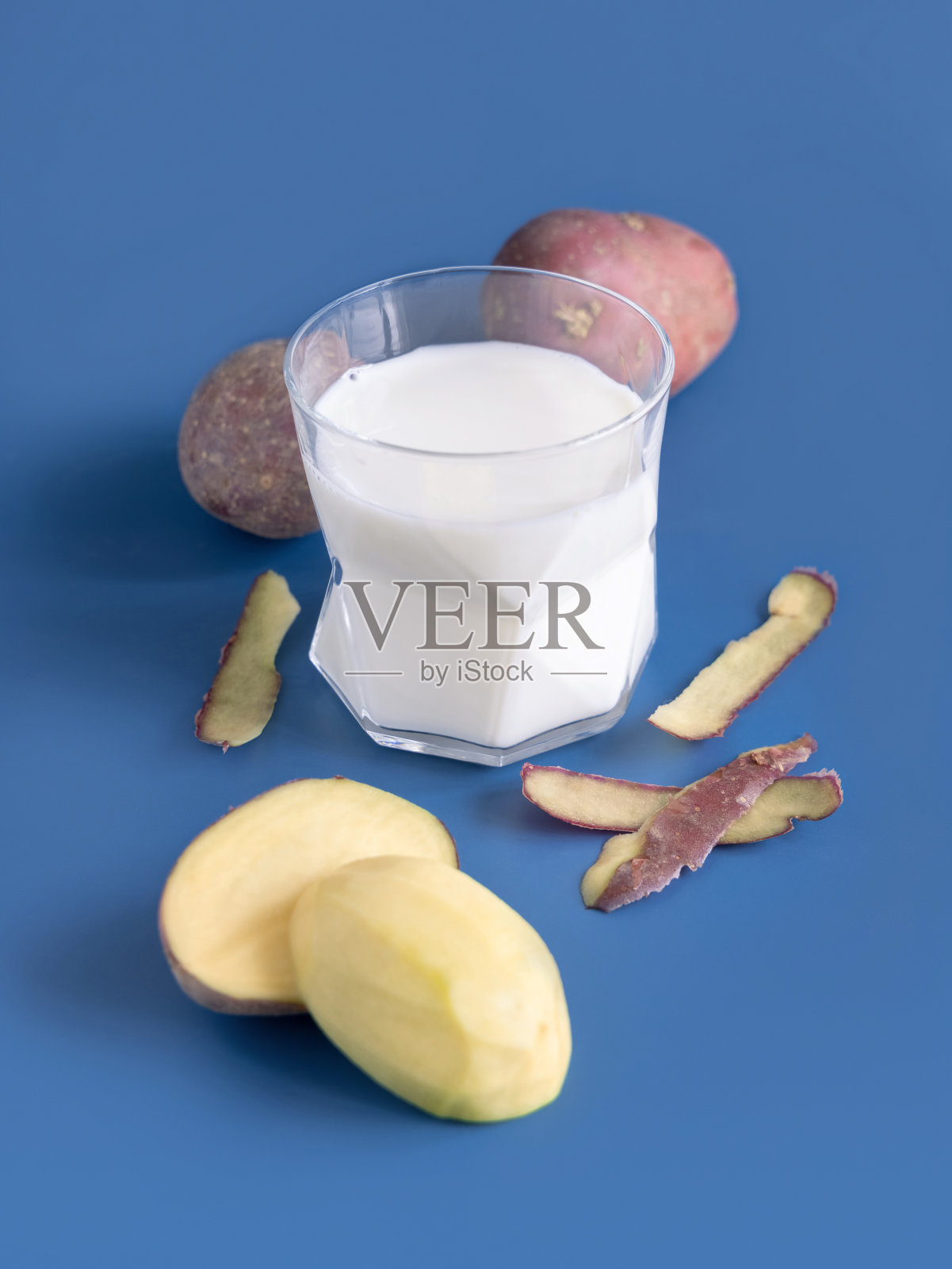 蓝色桌子上靠近马铃薯块茎的蔬菜土豆牛奶照片摄影图片