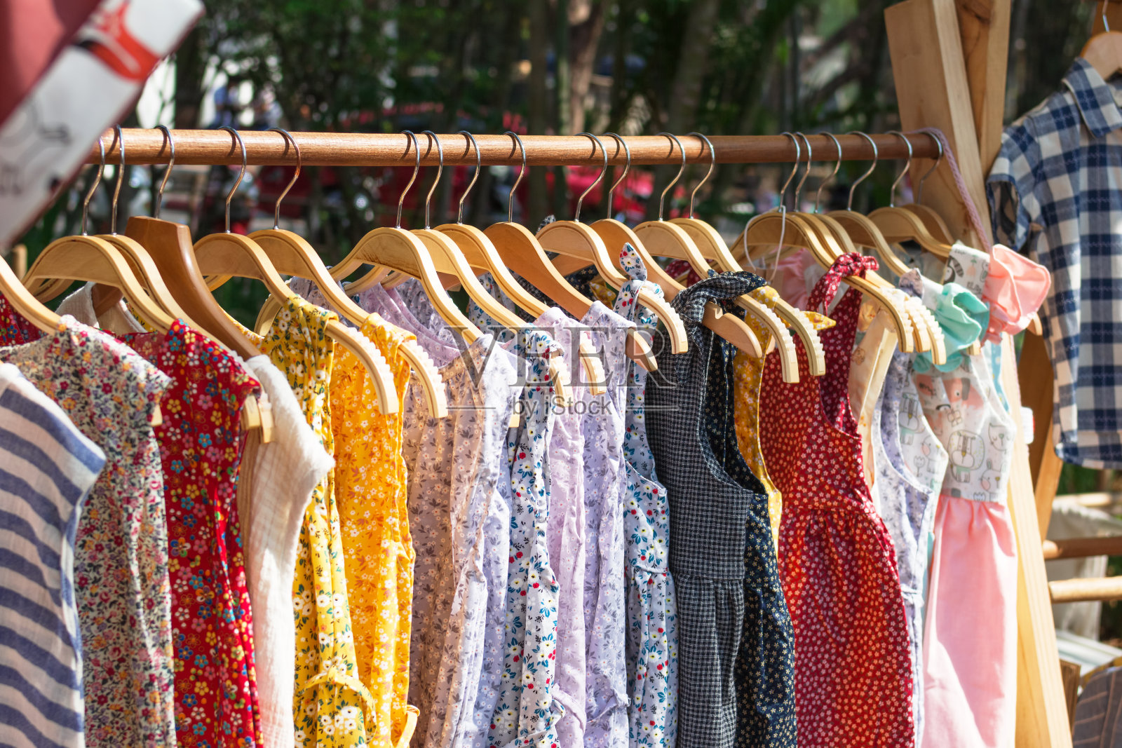 木制衣架，还有衣架和五颜六色的裙子。在街市上展示服装。照片摄影图片