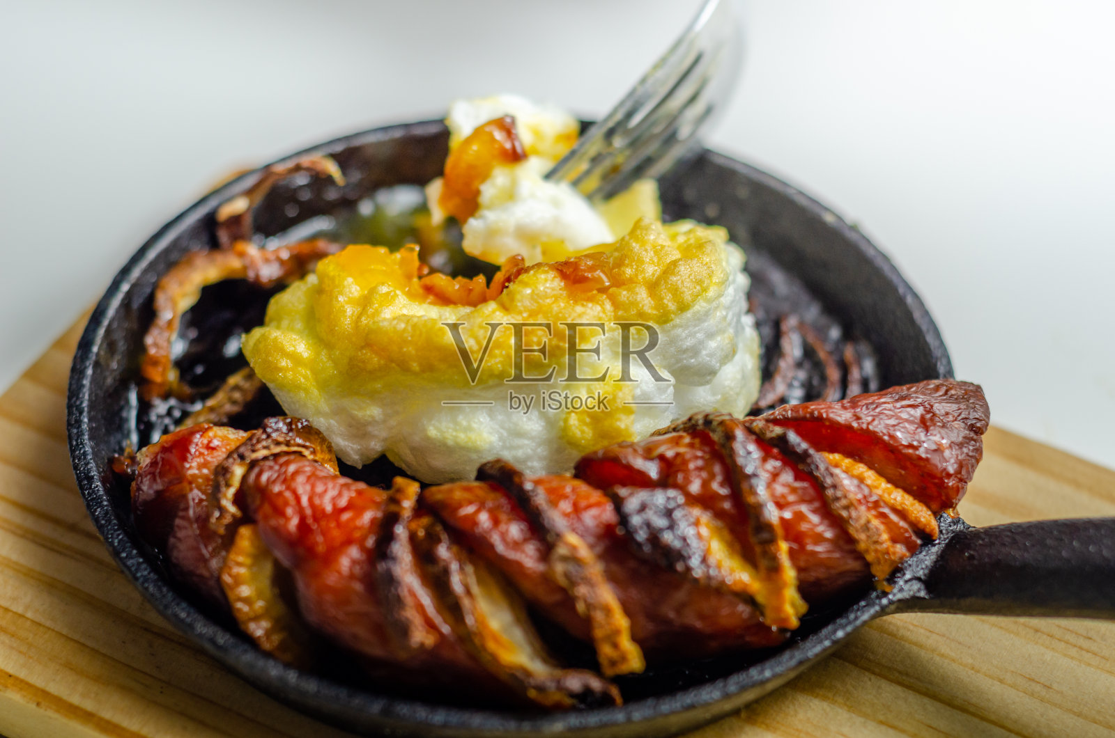 在云中吃着烤香肠、洋葱和鸡蛋，都是用铸铁锅盛着的照片摄影图片