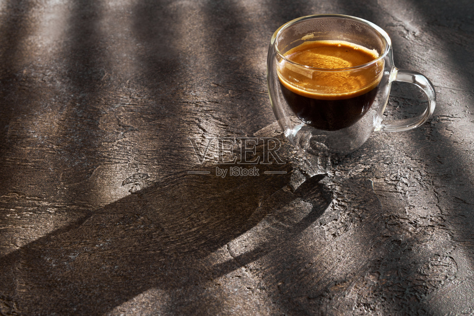 一杯早晨的双份浓缩咖啡，在阳光下，放在有深色纹理的桌子上照片摄影图片