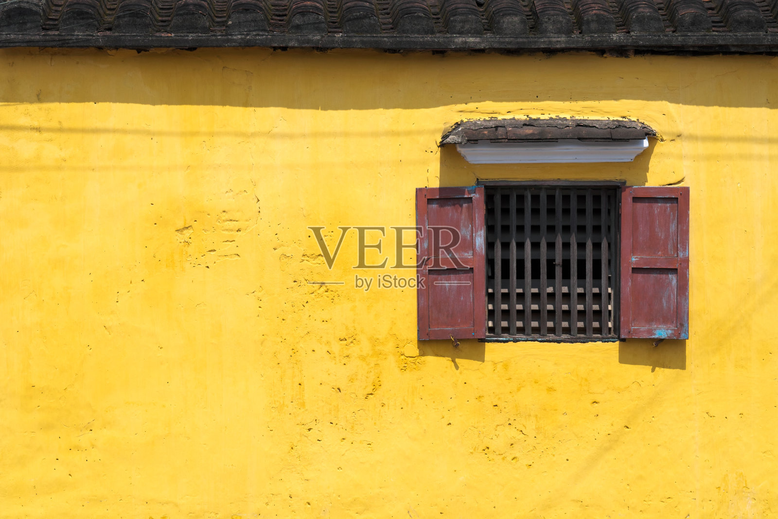 老旧的黄色水泥墙上的老式窗户。照片摄影图片