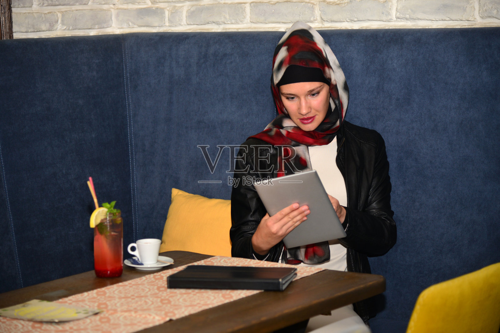 一位年轻的穆斯林妇女在café网站上工作。照片摄影图片