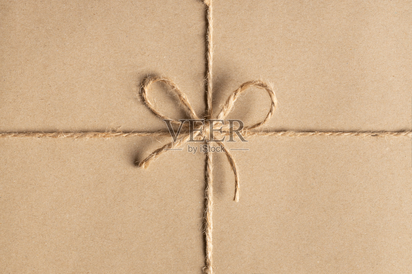 在再生纸背景上绑在一个蝴蝶结的麻绳的特写照片摄影图片