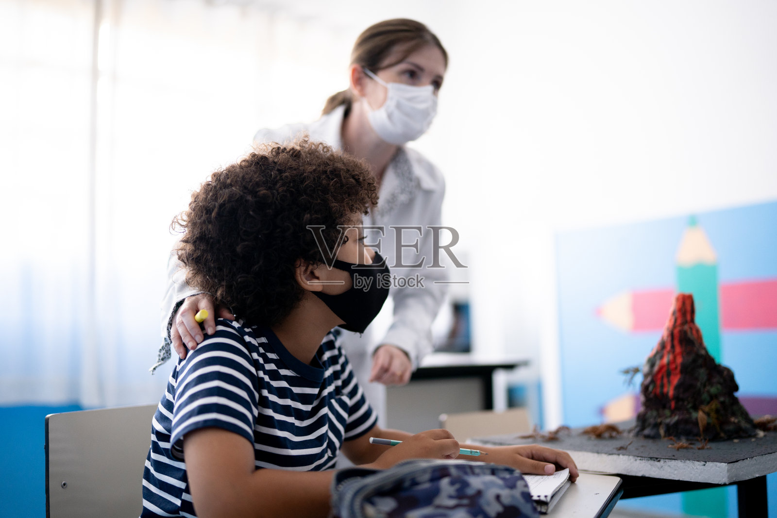 老师在教室里用口罩帮助学生上课照片摄影图片