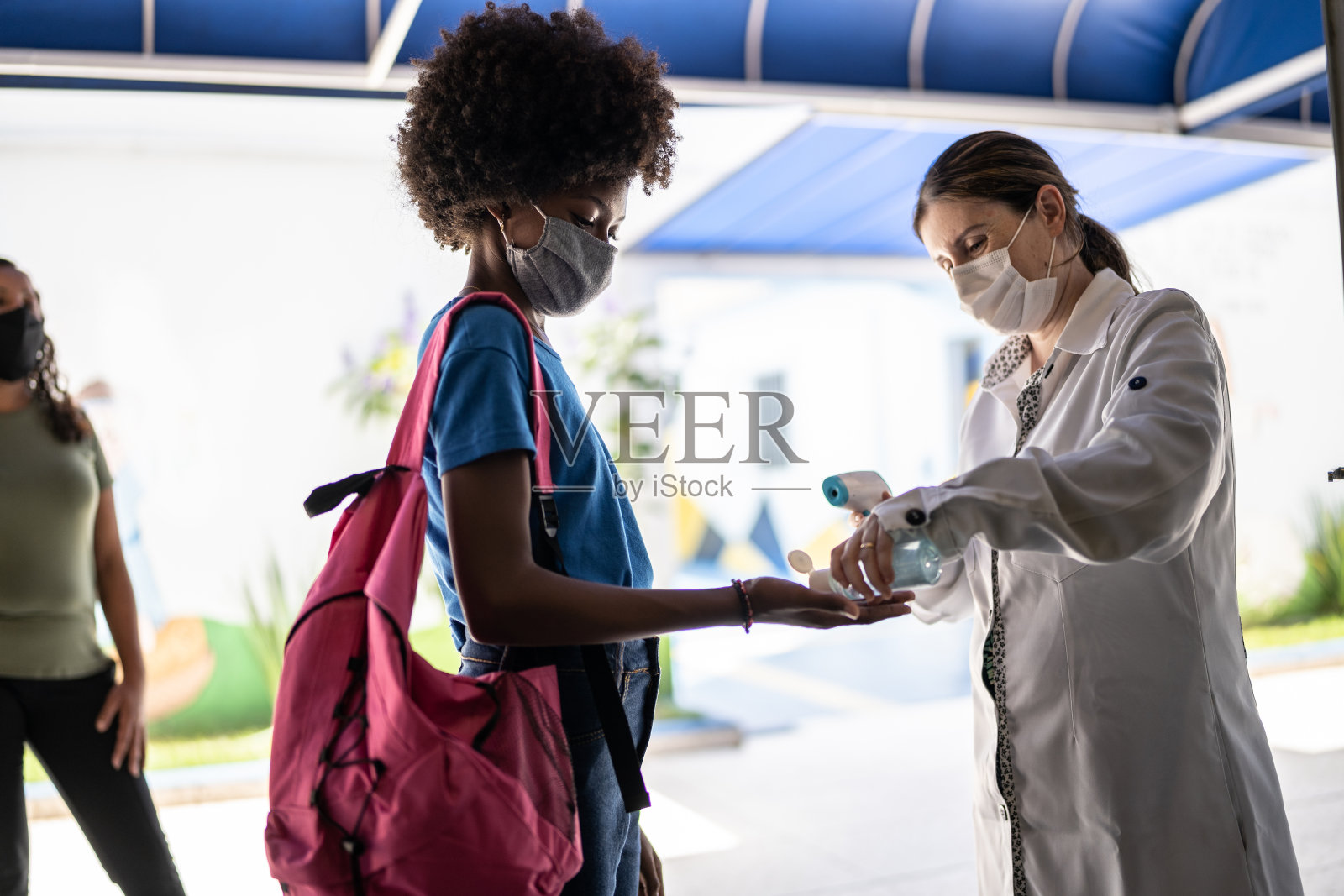 老师在学生入校前给学生用洗手液，并使用口罩照片摄影图片