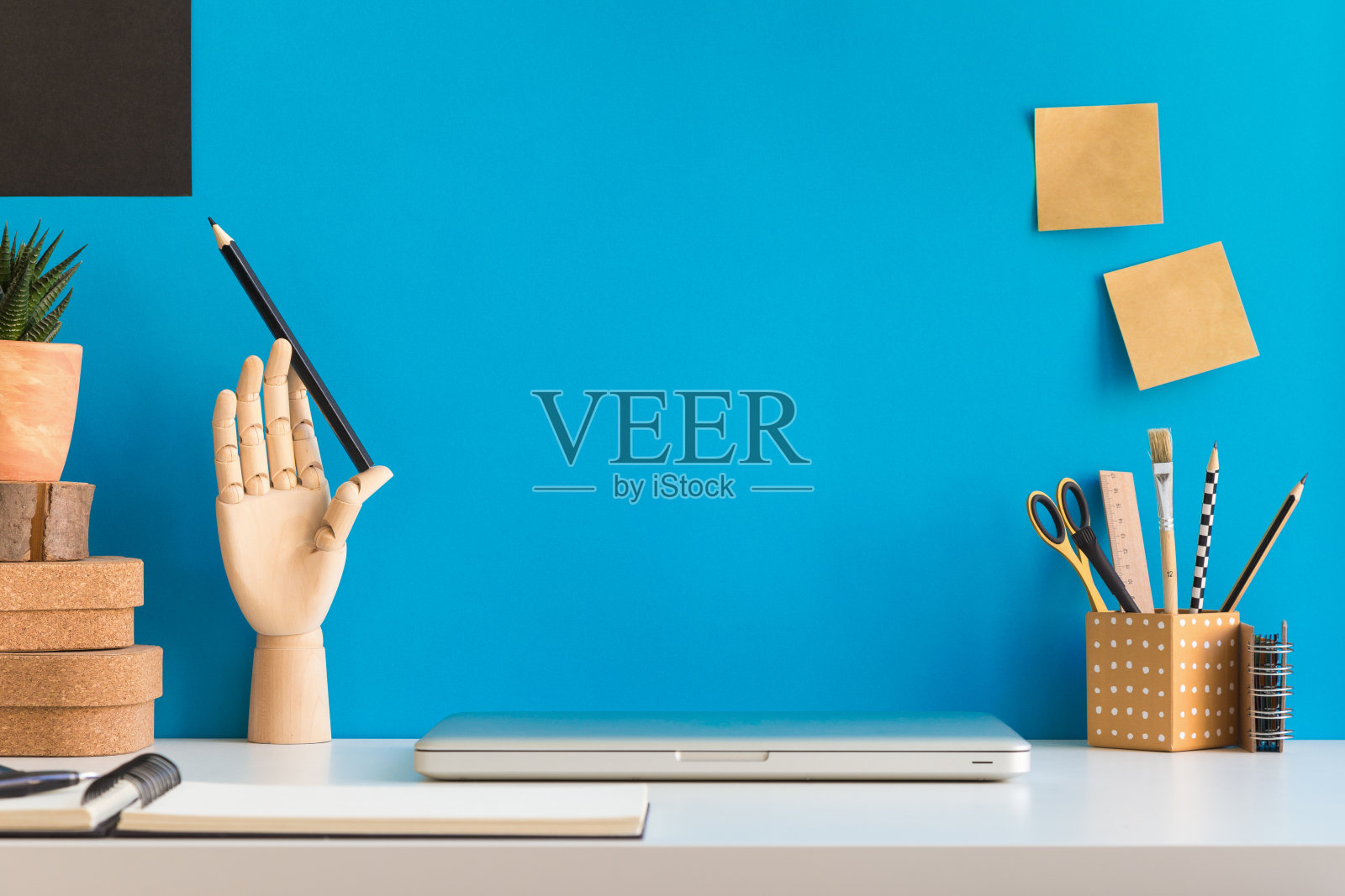 笔记本电脑在家庭办公室办公桌与用品靠蓝色的墙。照片摄影图片