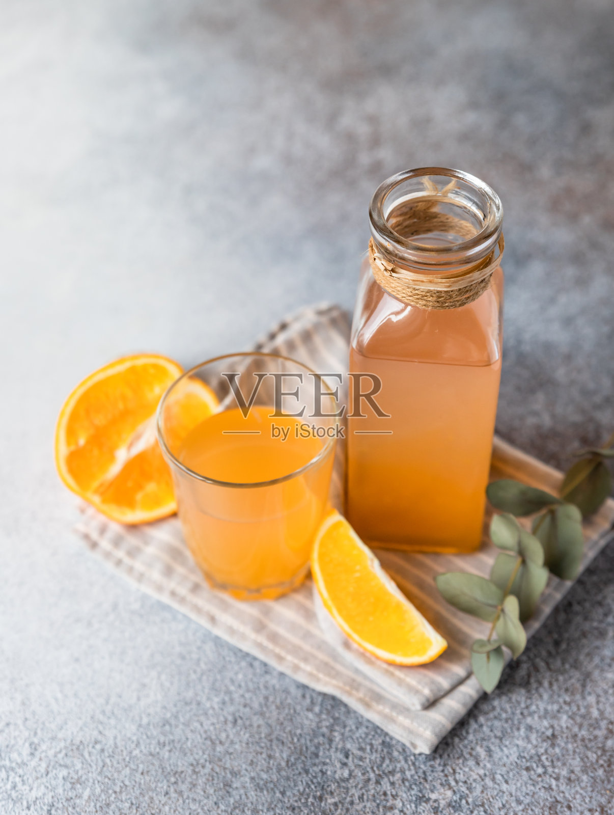 清凉的新鲜橙汁在玻璃和瓶子与新鲜的橙色，灰色背景。照片摄影图片