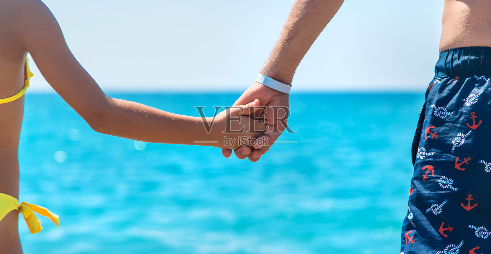 孩子和父亲手牵着手沿着海滩走。有选择性的重点。照片摄影图片