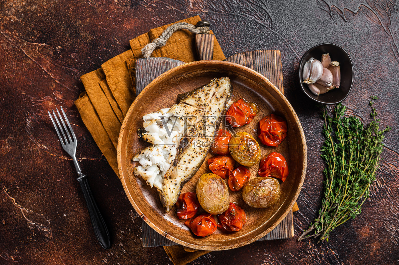 木盘烤比目鱼配烤番茄和土豆。黑暗的背景。俯视图照片摄影图片