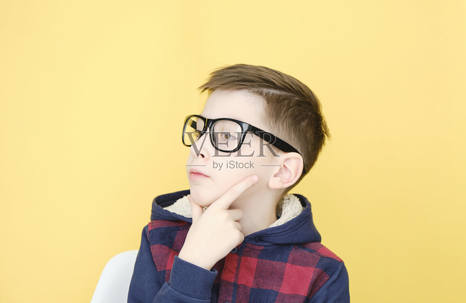 一头金发，戴着一副黄色眼镜的沉思男孩照片摄影图片
