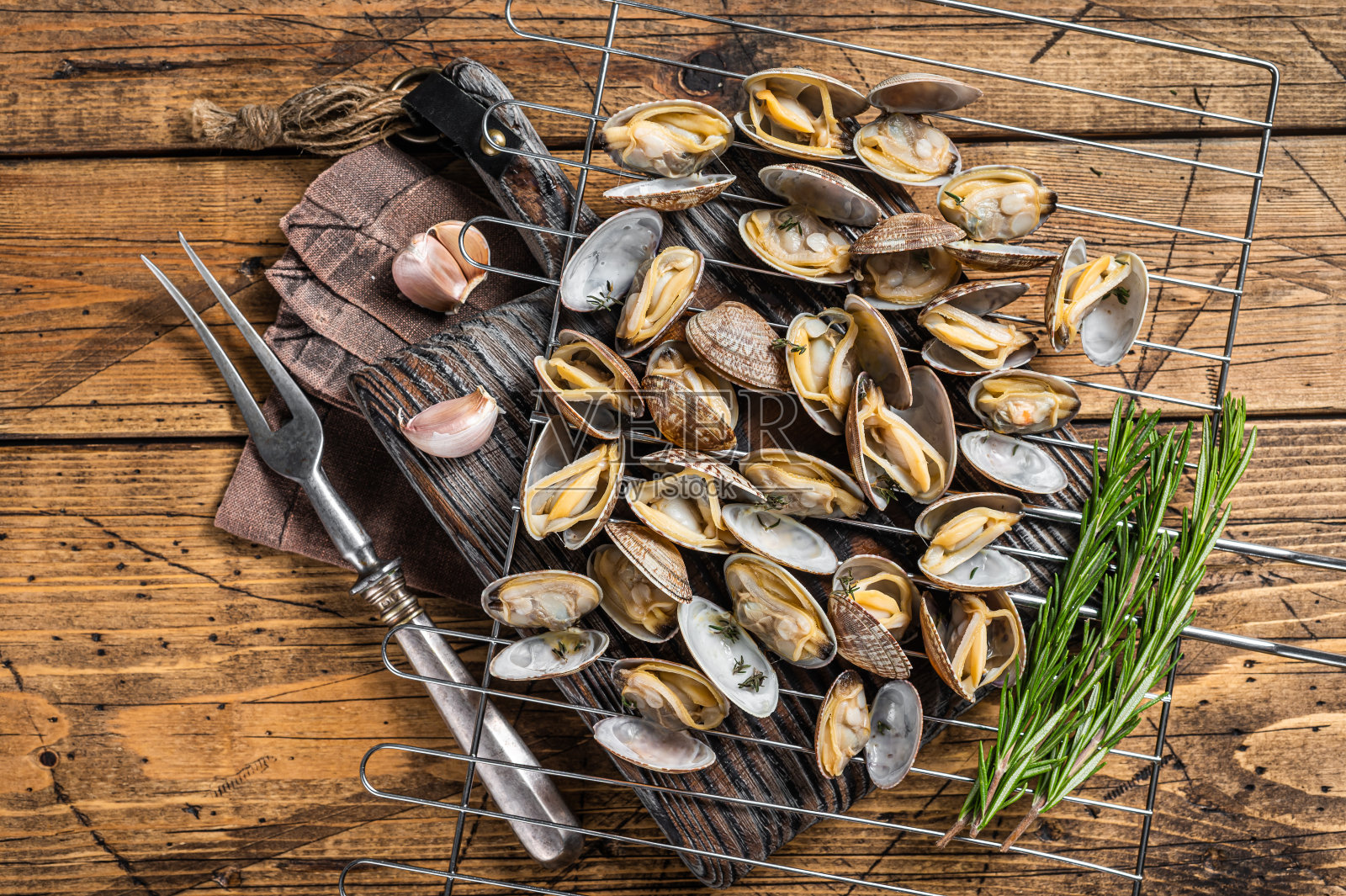 煮熟的贝壳蛤蜊，烤肉，大蒜和迷迭香。木制背景。俯视图照片摄影图片