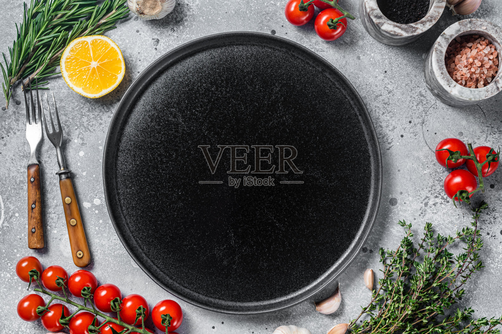 食物烹饪和健康饮食背景，以空质朴的盘子和新鲜的调味料，刀叉和蔬菜配料。灰色的背景。前视图。本空间照片摄影图片