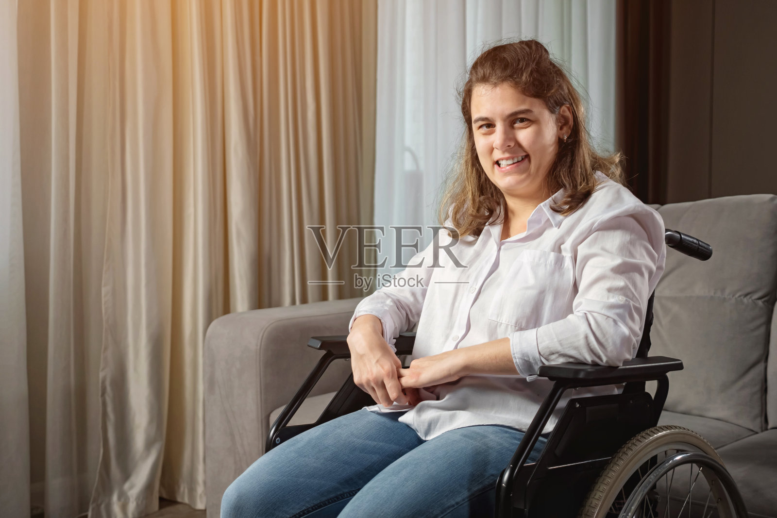 残疾妇女坐在沙发边的轮椅上微笑照片摄影图片