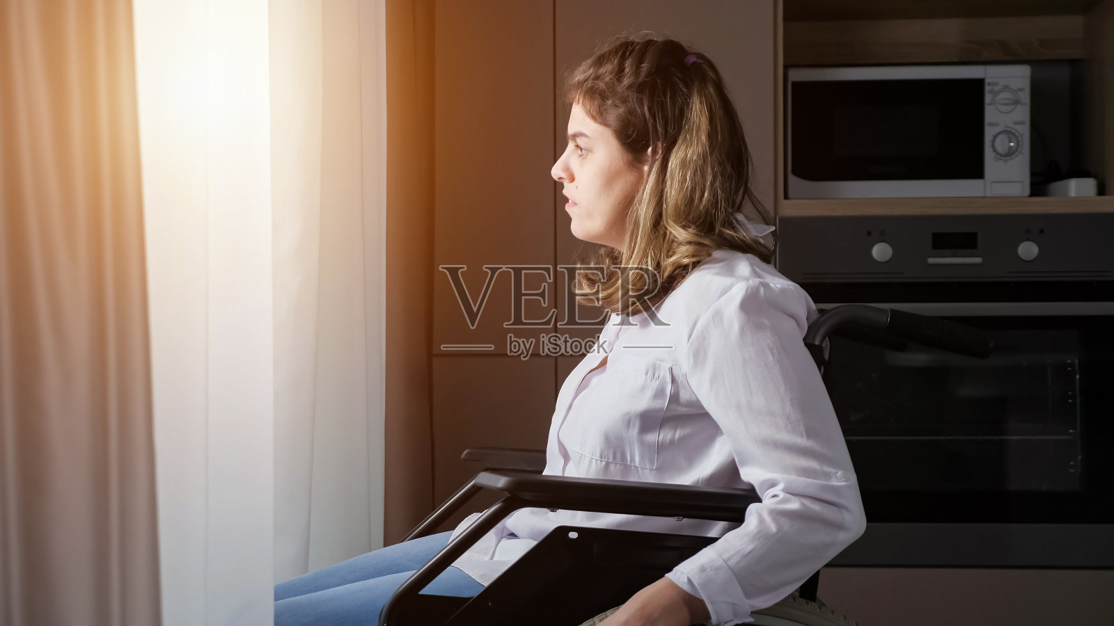 一位残疾妇女坐在轮椅上靠近窗户照片摄影图片