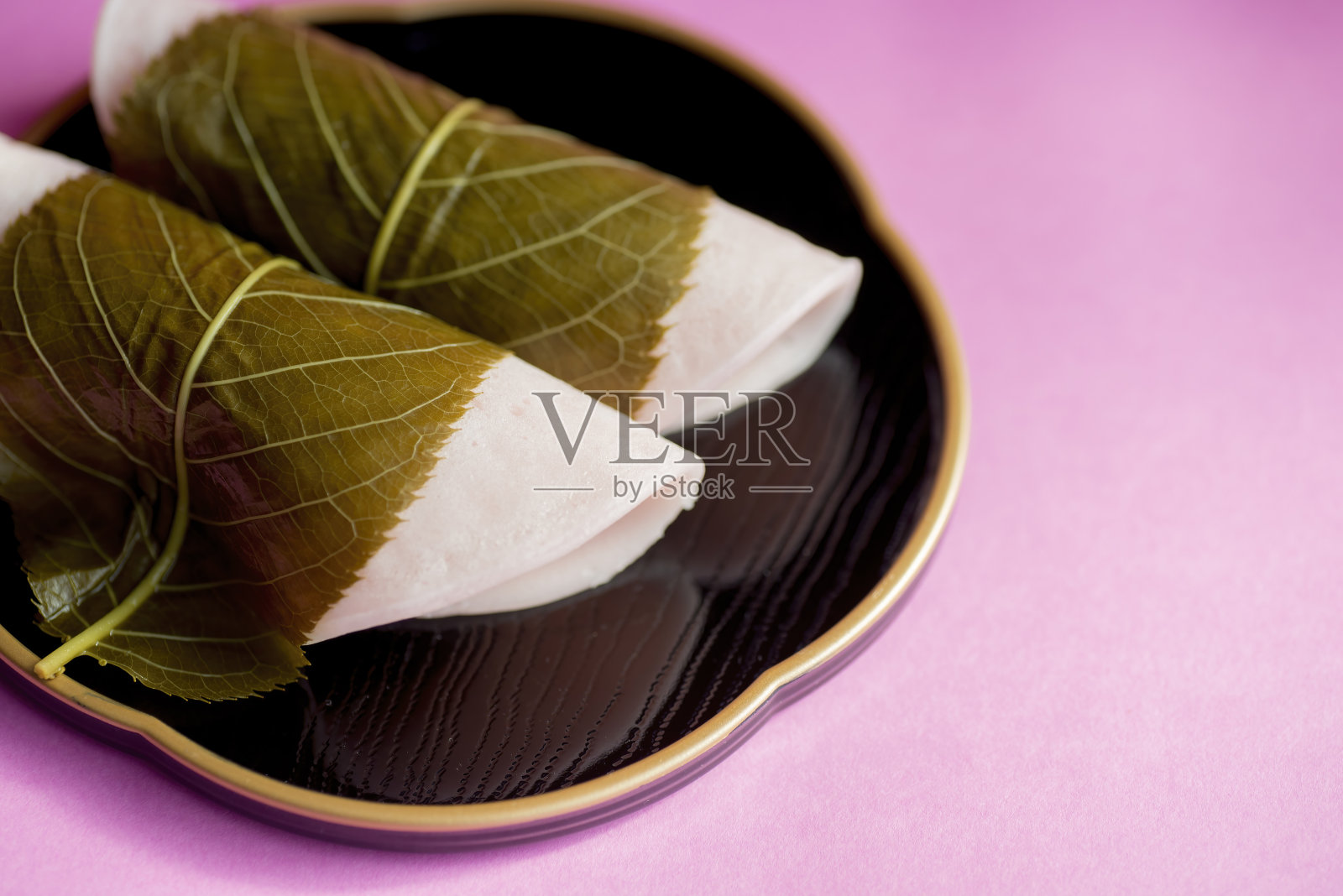 日本甜点樱花麻糬的特写镜头，放在一个黑色的盘子上。照片摄影图片