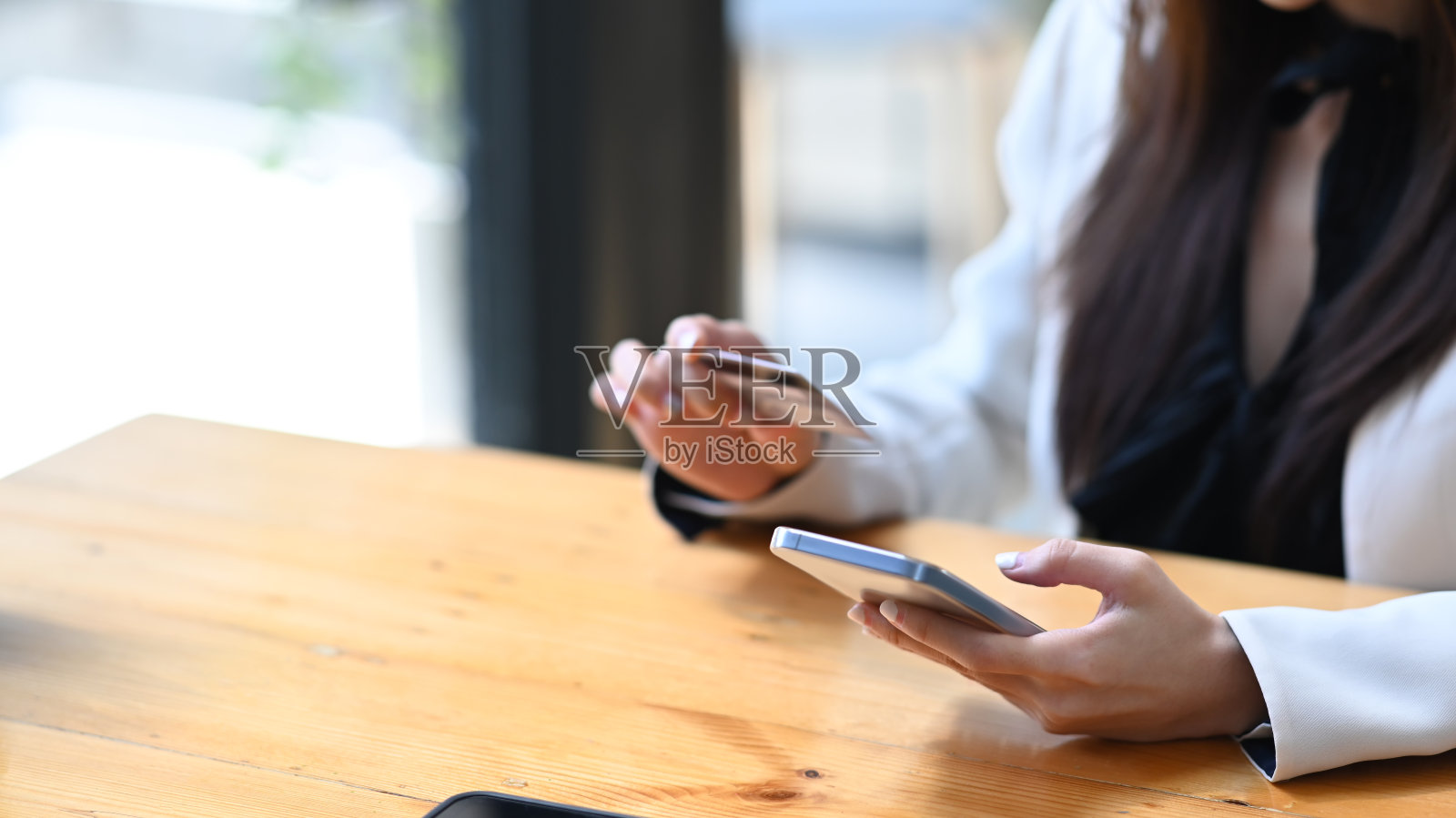 剪裁拍摄的年轻女商人在她的智能手机上在线支付。照片摄影图片