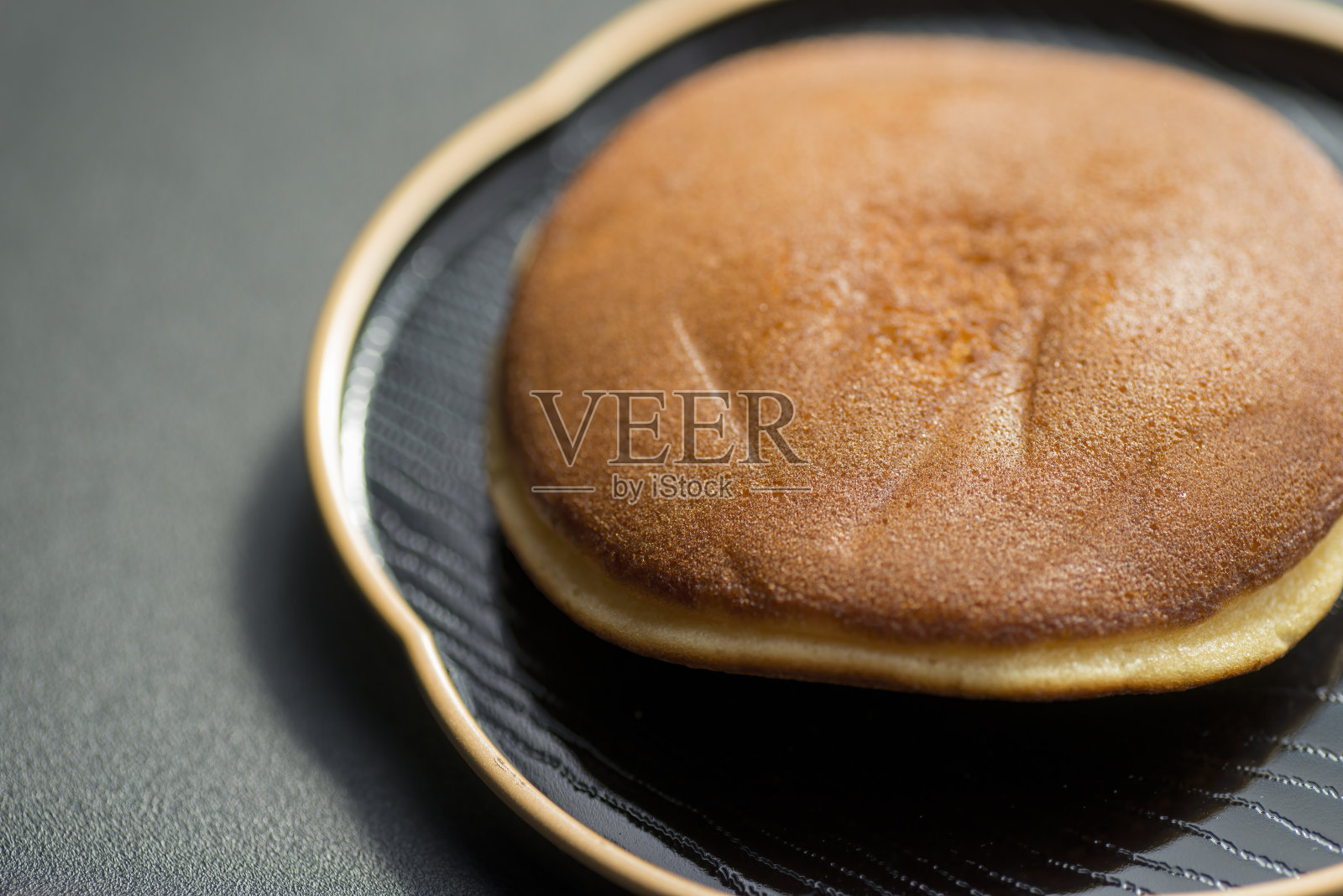 黑色盘子上的日式甜鱼烧。照片摄影图片