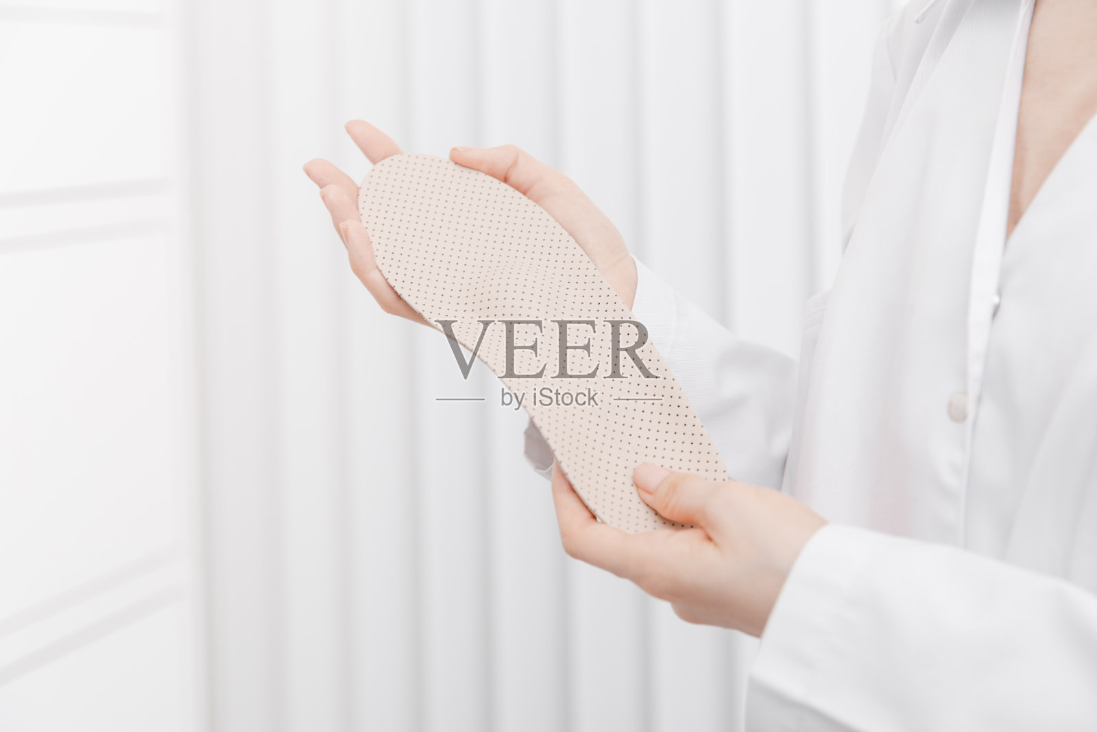 医生手里拿着矫形鞋垫。骨科医生测试医疗设备。矫形鞋垫上的白色。足部护理。扁平足的修正。预防扁平足和足部疾病照片摄影图片