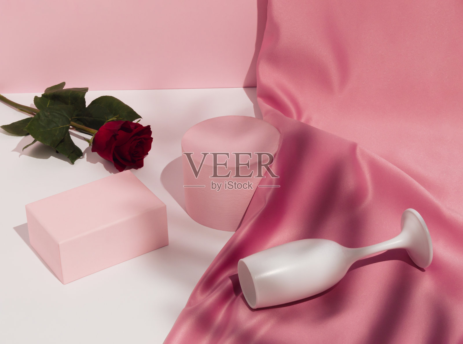 浪漫粉色情人节构图：酒杯、绸缎、红玫瑰和展示台照片摄影图片