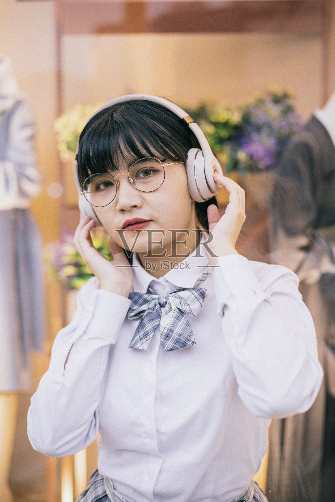 可爱的亚洲女学生戴着耳机听音乐，走在街上照片摄影图片