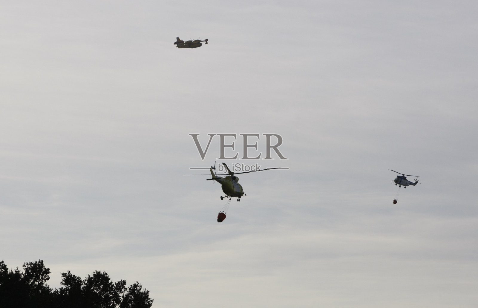 在森林大火中飞行的两架直升机和一架灭火飞机的剪影照片摄影图片