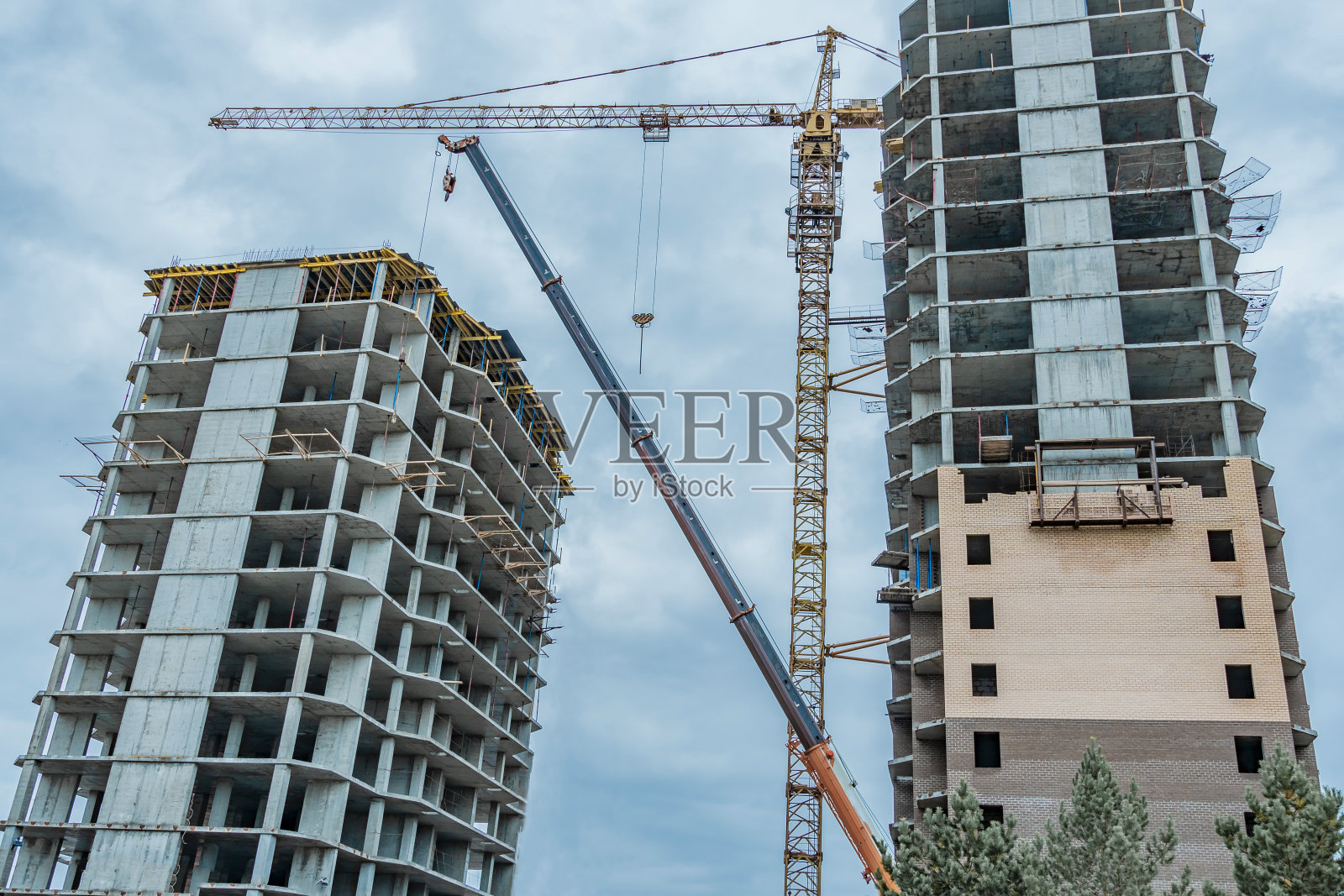 施工现场用起重机。长期的建设。一个正在建设中的新建筑，自底向上的视图。未完成的摩天大楼,冻结施工。一幢多层住宅尚未完工照片摄影图片