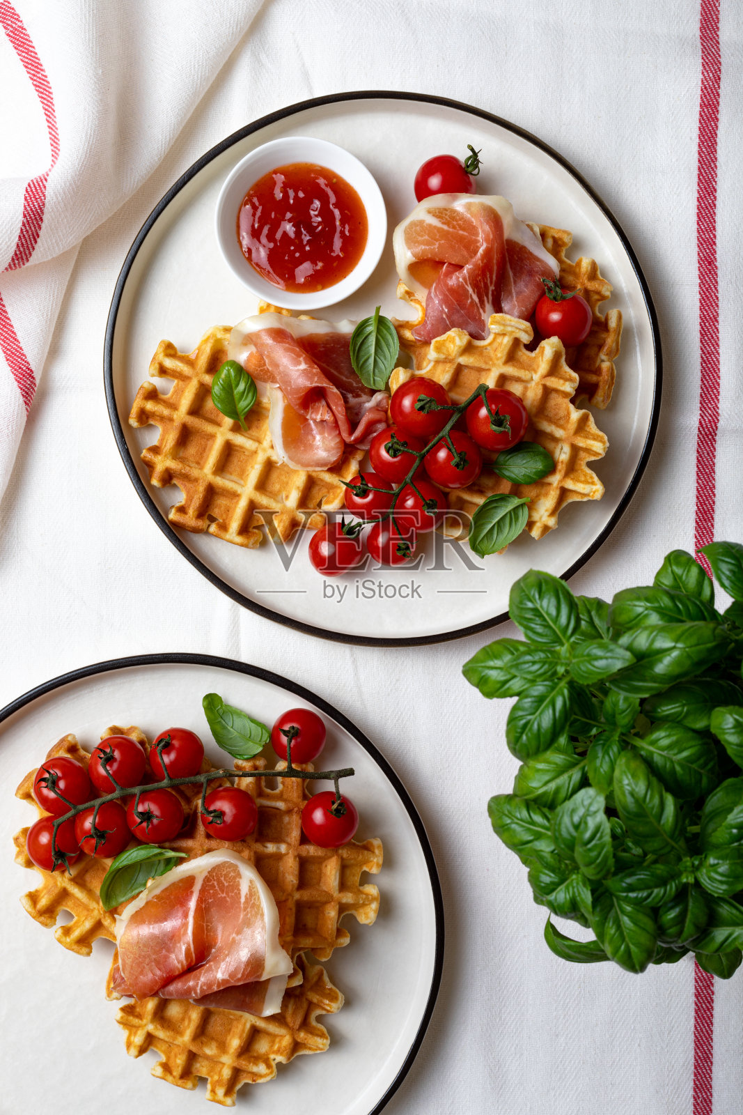 比利时土豆味的华夫饼配意大利熏火腿、圣女果、罗勒叶和热番茄酱或辣酱。早餐，早午餐，浅色背景照片摄影图片
