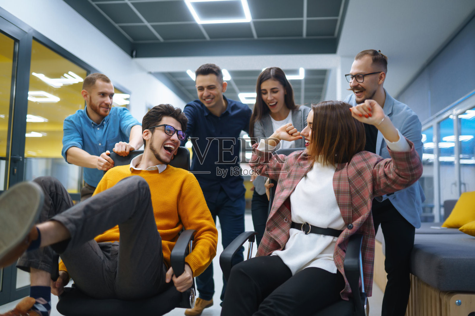 年轻开朗的商务人士在办公室的椅子上玩得很开心，面带微笑。照片摄影图片