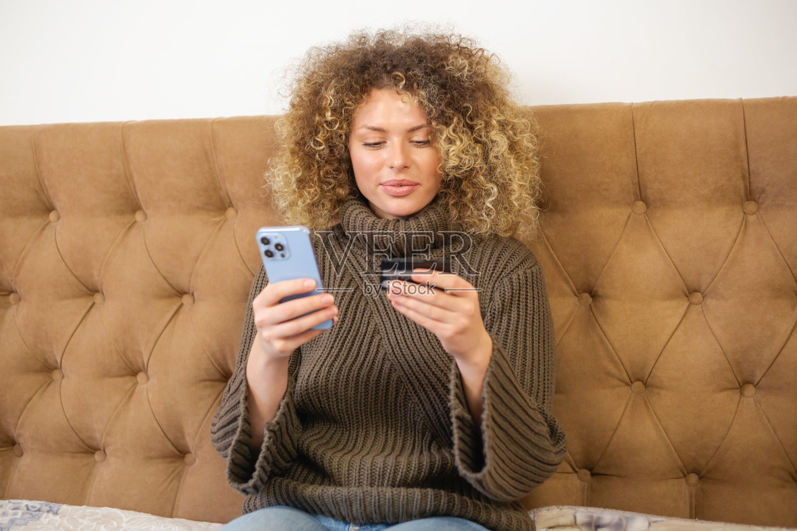 用信用卡和手机在线购物。快乐的白人女性用现代智能手机支付，脸上带着欢快的微笑。客户在手机购物应用中使用银行卡付款照片摄影图片