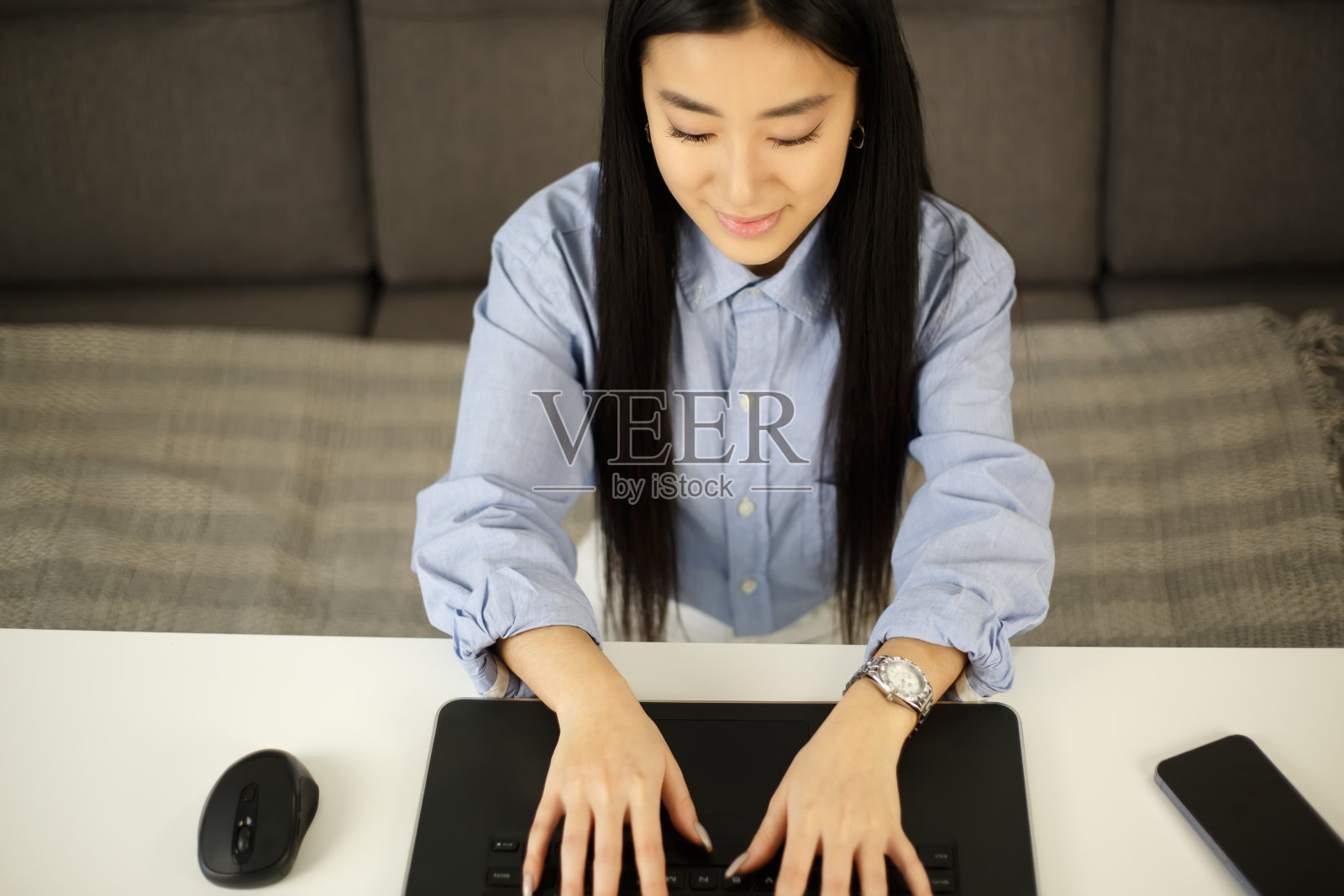 一名年轻的亚洲女性在家中用笔记本电脑键盘打字。开朗的越南女性在笔记本电脑上工作。企业家在网上做远程工作照片摄影图片