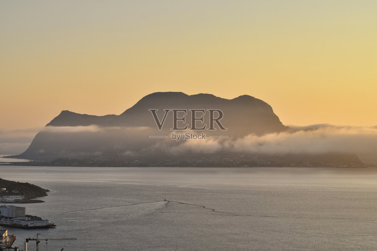 在挪威北部的奥勒松镇，橙色的夕阳映照在海边。极地日的日落。照片摄影图片